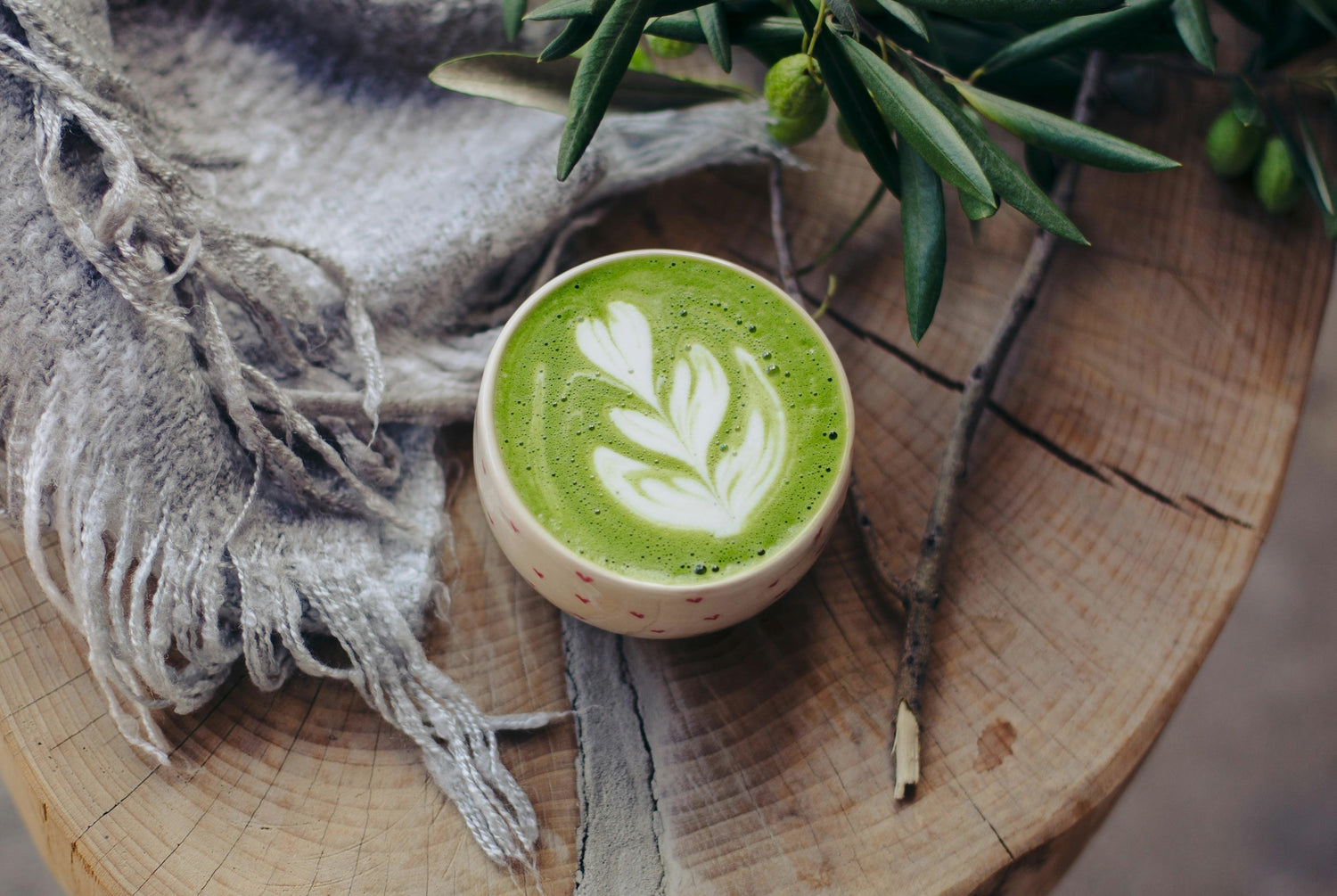 What Is Matcha Green Tea? Everything You Need to Know, image of a cup of matcha green tea on wood table with blanket